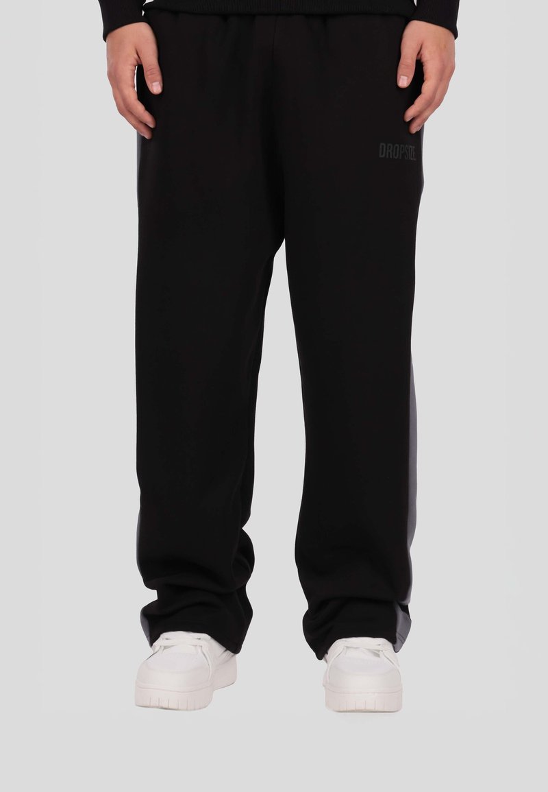 Czarne spodnie dresowe wykonane z miękkiego materiału, charakteryzujące się prostym krojem nogawki i elastycznym pasem. Subtelne logo marki po boku.
