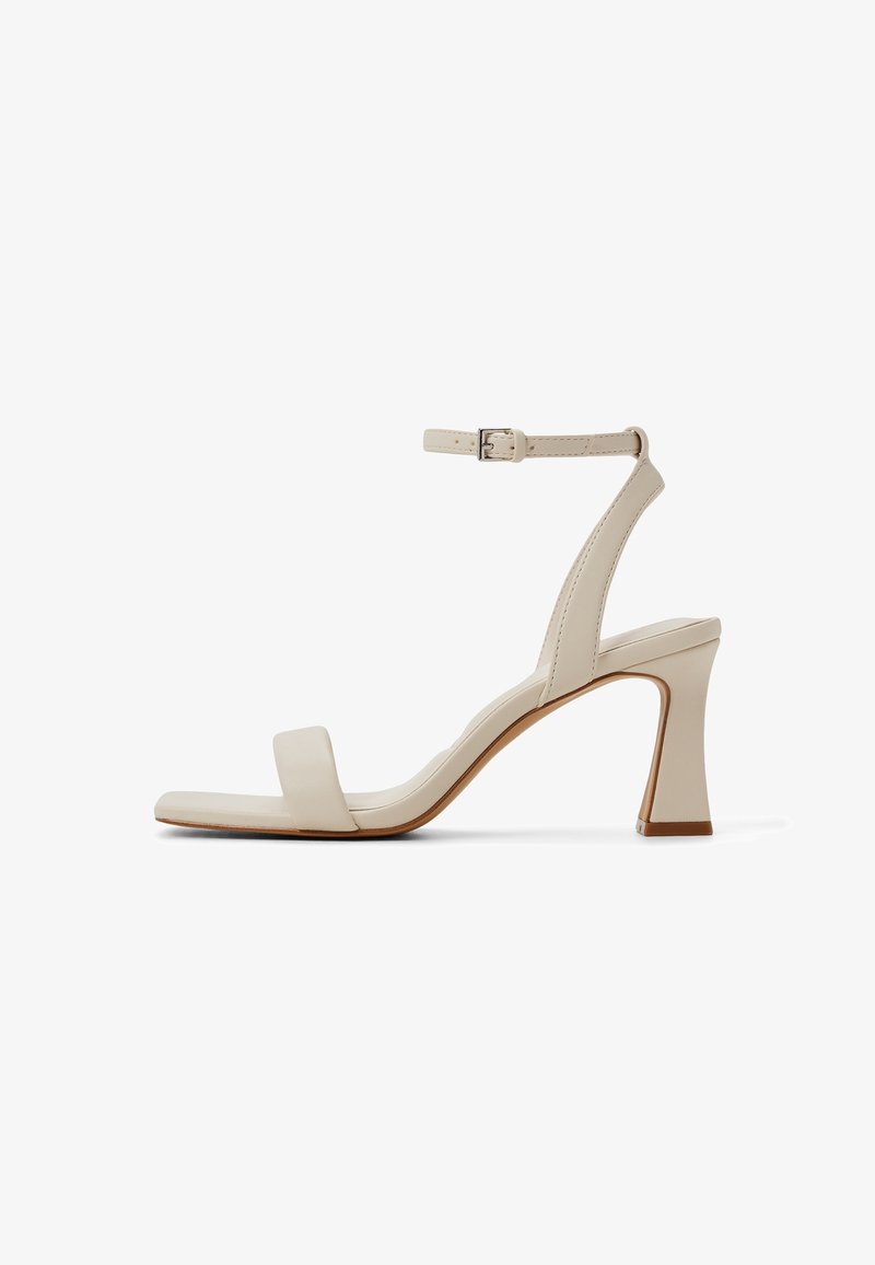 Beige leather high-heeled sandal with an ankle strap, square toe, and a chunky heel. Smooth texture with minimalistic design details.