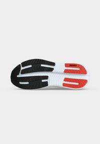 Running shoe sole with black, white, and red traction patterns and the brand name Brooks on the front right side.