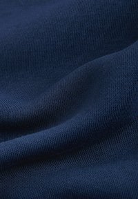 Tengerészkék kötött szövet sima textúrával, egységes, finom mintával és lágy eséssel, ruházati felhasználásra alkalmas.