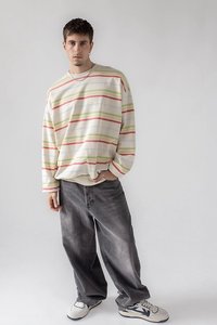 Striped long-sleeve shirt in cream with red, green, and blue lines, paired with loose grey jeans and white sneakers with black accents.