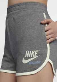 Gray athletic shorts with white trim and side pockets; features a large Nike logo in white and blue on the lower left side.