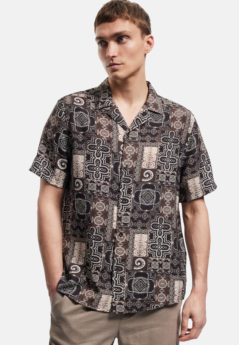 Kurzärmeliges, knöpfbares Hemd aus gemustertem Stoff in Dunkelbraun mit weißen geometrischen Designs und Akzenten. Verfügt über eine lässige Passform.