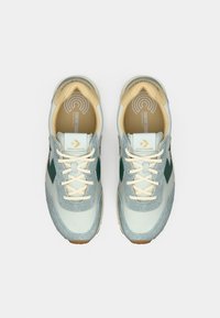 Light blue sneakers with green accents, suede and mesh materials, rounded shape, white laces, and logo on tongue and side.