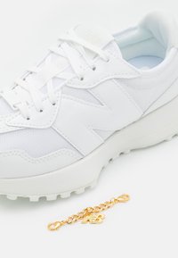 Weiße Sneaker aus Mesh und synthetischem Material, runde Zehenpartie, strukturierte Oberfläche, flache weiße Schnürsenkel und eine goldene Marken-Kette angebracht.