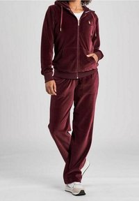 Burgundy velour träningsdräkt med en zip-up hoodie med fickor, matchande byxor och elastiska muddar och midja.