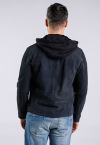 Svart läderjacka med en svart huva under, med en slät yta och en figursydd design, visad bakifrån.