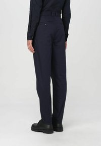 Pantaloni leggeri blu navy dal taglio dritto, con due tasche posteriori, passanti per cintura e una superficie liscia. Abbinati a scarpe nere stringate.