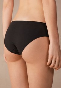 Culottes en coton noir avec une texture lisse et une couverture modérée ; présente un design simple avec des bords nets et sans matériel visible.