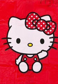 White cartoon cat with black eyes, yellow nose, red polka-dot bow, and red outfit, sitting against a red background.