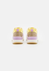 Sneakers with a mix of yellow mesh, beige patent leather, and purple accents. Thick white sole, padded collar, and logo detail on heels.