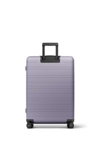 Valise rigide de couleur violet clair avec des rainures horizontales, une poignée télescopique noire et quatre roues noires.