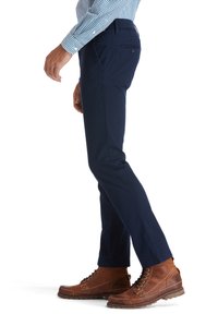 Chinos azul marino hechos de una resistente mezcla de algodón con un corte recto, que cuentan con bolsillos laterales y se llevan con botas de cordones marrones.