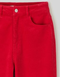 Pantalons en velours côtelé rouge avec une coupe droite, un design à cinq poches et une fermeture à bouton en métal argenté à l'avant. Texture douce et motif côtelé.