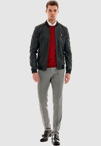 Schwarze Leder-Bomberjacke, roter Pullover, graue tapered Hose, schwarze Schnürschuhe. Glatte Textur, lässiges Design, keine sichtbaren Muster oder Logos.