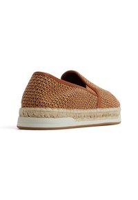 Woven brązowy tekstylny but wsuwany z naturalną środkową podeszwą z juty i gumową podeszwą. Posiada miękkie skórzane wykończenie wzdłuż krawędzi.