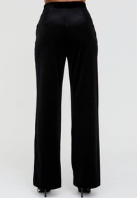 Schwarze, weit geschnittene Hose aus weichem Stoff mit glatter Textur, ausgestattet mit hoher Taille und Gesäßtaschen. Elegantes und vielseitiges Design.