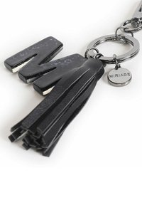 Portachiavi nero con lettera "M" lucida, un tassello nero testurizzato e un piccolo medaglione rotondo inciso con "MIRIADA". Finiture in tonalità argento.