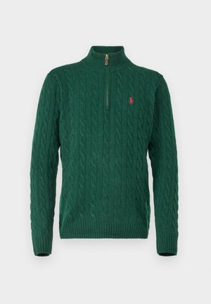 Sweater verde em malha com colarinho alto, apresentando um fecho de zip de um quarto, padrão de ponto cabos e um pequeno logótipo vermelho no peito.