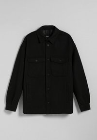 Černá košile s kovovým efektem, vyrobená z texturované látky, s špičatým límcem, předními knoflíky, dvěma náprsními kapsami a bočními kapsami v švu.