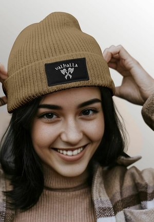 Brown ribbed beanie with a black rectangular patch featuring the word "valhalla" and crossed axes design. Soft texture, snug fit.