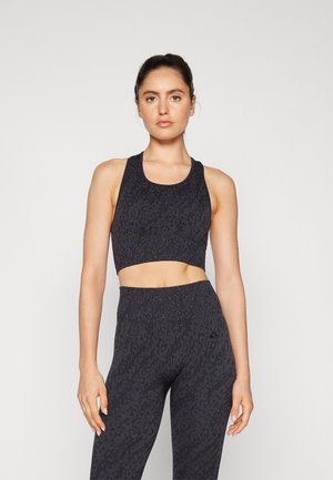 Crop top de sport noir avec un imprimé léopard texturé, sans manches et avec un col arrondi, associé à un legging taille haute assorti.