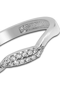 Bague en argent avec un anneau lisse, ornée d'une rangée de petites pierres transparentes disposées en design ovale sur le dessus et un détail texturé à l'intérieur.