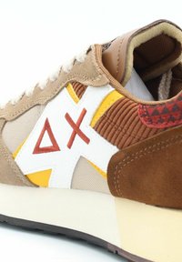 Sneaker multicolore con materiali beige, marrone e bianchi, dettagli gialli, texture in corduroy e ricamo del logo distintivo.