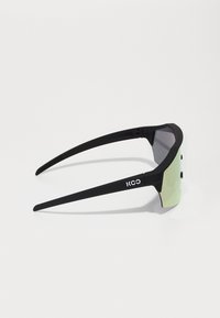 Schwarze Sonnenbrille mit geometrischem Rahmen, spiegelnden grünen Gläsern und schlanken schwarzen Bügeln mit strukturiertem Griff. Logo an der Seite aufgedruckt.