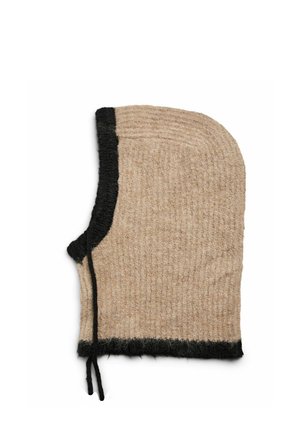 Mujer ajustándose una capucha beige y negra de punto, usada sobre una chaqueta de cuero negro con bolsillos con cremallera, sobre un fondo liso.