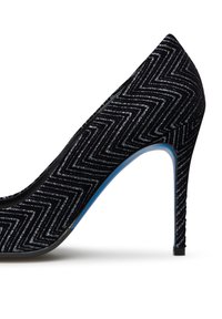 Scarpa con tacco alto nera con una trama a zigzag testurizzata, caratterizzata da una punta appuntita e un accento blu sulla suola. Texture con brillantezza metallica.