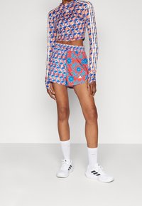 Crochet-setti, jossa on pitkähihaisia lyhyitä ykkösiä ja shortseja, joissa on sinisiä, oransseja ja punaisia kukka- ja geometrisia kuvioita. Valmistettu kevyestä kankaasta.