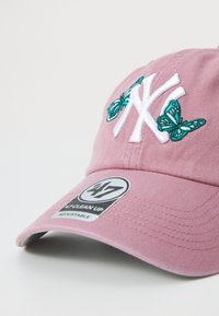 Rosa Baumwollmütze mit weißem gesticktem NY-Logo und türkisfarbenen Schmetterlingen. Enthält ein Etikett mit der Aufschrift "47 CLEAN UP" und einen verstellbaren Riemen.