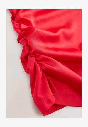 Raudonas audinys su lygiu paviršiumi, šonuose surinktais raukiniais ir siūtu kraštu. Medžiaga atrodo lengva ir tampri.