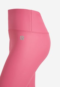 Leggings rosa realizzati in tessuto liscio ed elastico. Presentano un logo argentato sul lato sinistro e cuciture piatte per il massimo comfort.