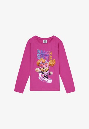 Maglietta a maniche lunghe rosa con un cane dei cartoni animati in costume da supereroe, con la frase "RAGGIUNGI IL CIELO" in un testo colorato.