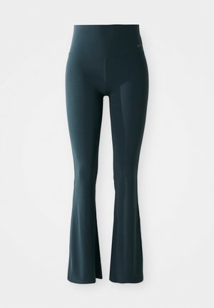 Leggings acampanados en azul oscuro con cintura alta, fabricados en tejido elástico. Presentan un sutil detalle de logo cerca de la cintura. Textura suave.