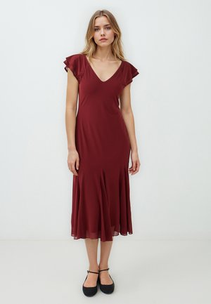 Bordeaux midi-jurk met een V-hals, fladdermouwen en een uitlopende zoom. Gemaakt van een gladde stof met een lichte textuur. Zwarte flat sandals gedragen.