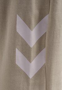 Helles taupe-farbenes Gewebe mit zwei großen weißen Chevron-Streifen. Die Struktur ist gestrickt, was ein dezentes, atmungsaktives Muster erzeugt.