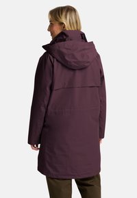 Lange, kapuzenjacke in tiefem Lila, hergestellt aus glattem, wasserabweisendem Stoff. Verfügt über eine Rückenpasse und einen entspannten Schnitt, mit minimalen Nähten.