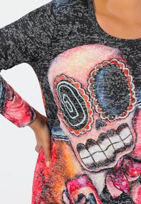Long-sleeve top featuring a colorful skull graphic. Material is soft and textured with black, red, and orange patterns, and embellishments on the skull.