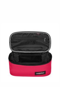 Bolsa de almacenamiento rectangular roja hecha de tela resistente. Interior gris con un bolsillo de malla y cierre de cremallera. Logo de Eastpak visible.