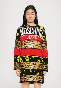 Juoda ir geltona megzta suknelė su dideliu raudonu ir baltu "MOSCHINO JEANS" logotipu, gėlių ir tigro juostelėmis, ilgomis rankovėmis ir laisvu siluetu.