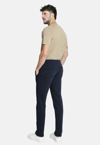 Camiseta corta de manga en color beige combinada con pantalones de cintura elástica en color azul marino, que exhiben un corte relajado y zapatillas blancas.