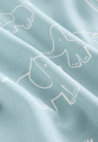 Heleda sinine kangas valgete elevantide mustriga, näidates pehmet tekstuuri ja mängulist disaini, millel on ümarad kujundid ja lihtsustatud kontuurid.