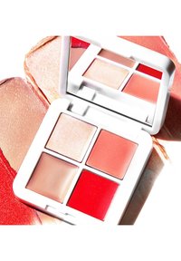 Palette de maquillage compacte avec quatre sections : un illuminateur pailleté, deux blushs crémeux en teintes roses et un rouge vibrant. Coffret blanc et miroir.