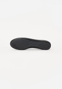 Semelle de chaussure noire avec un motif texturé, bords lisses et un talon légèrement surélevé. Le matériau semble caoutchouté avec une finition mate.
