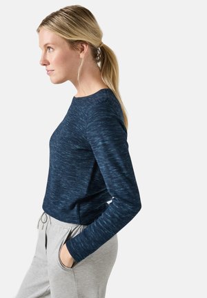 Haut à manches longues bleu marine en tissu texturé, avec un col rond et une coupe ajustée, associé à un pantalon de jogging gris clair avec poches.