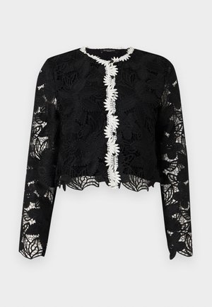 Schwarzer langer Spitzenstrickcardigan mit weißem Blumenbesatz entlang der geknöpften Vorderseite und gewelltem Saum sowie Manschetten.