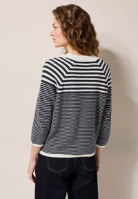 Marinblå och vit randig stickad tröja med rund hals, trekvartsärmar och mönster med textur. Ribbad nederkant och ärmslut.